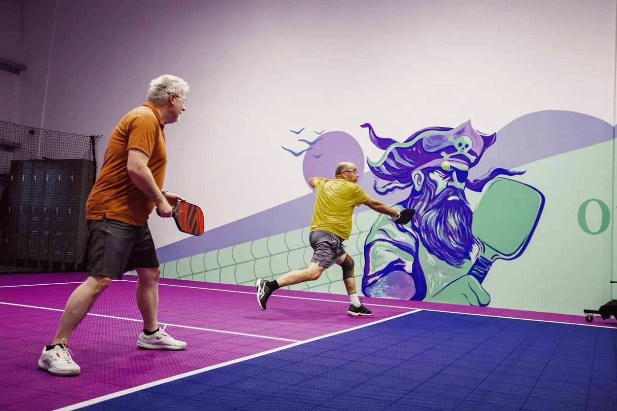 Wide view of the purple, pink and blue private pickleball court at Pickleball Cove